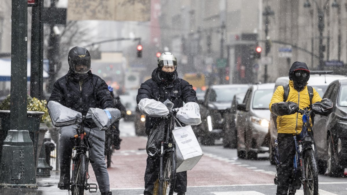 Personas en bicicletas de reparto se abrigaron contra la nieve que caía durante una tormenta de invierno en Nueva York, Nueva York, EE.UU., 19 de enero de 2024.