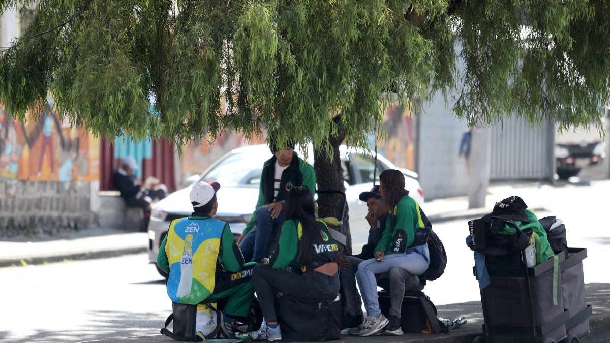 Trabajadores en Quito buscan la sombra durante las horas de altas temperaturas en la capital