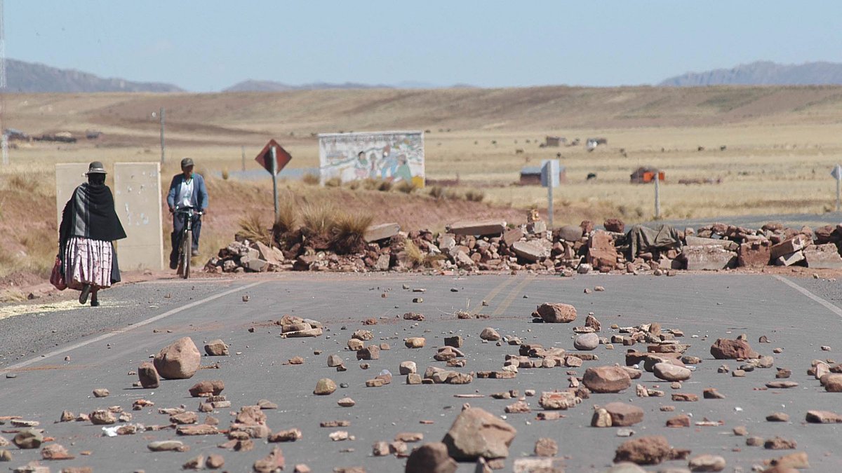 Indígenas aparecen junto a una carretera en Tiwanacu (Bolivia), que ha sido bloqueada.