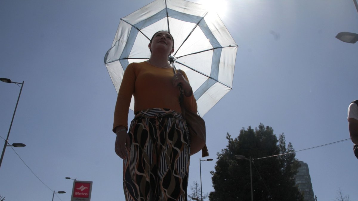 Las personas se cubren del sol con vestimentas largas y sombrilla.