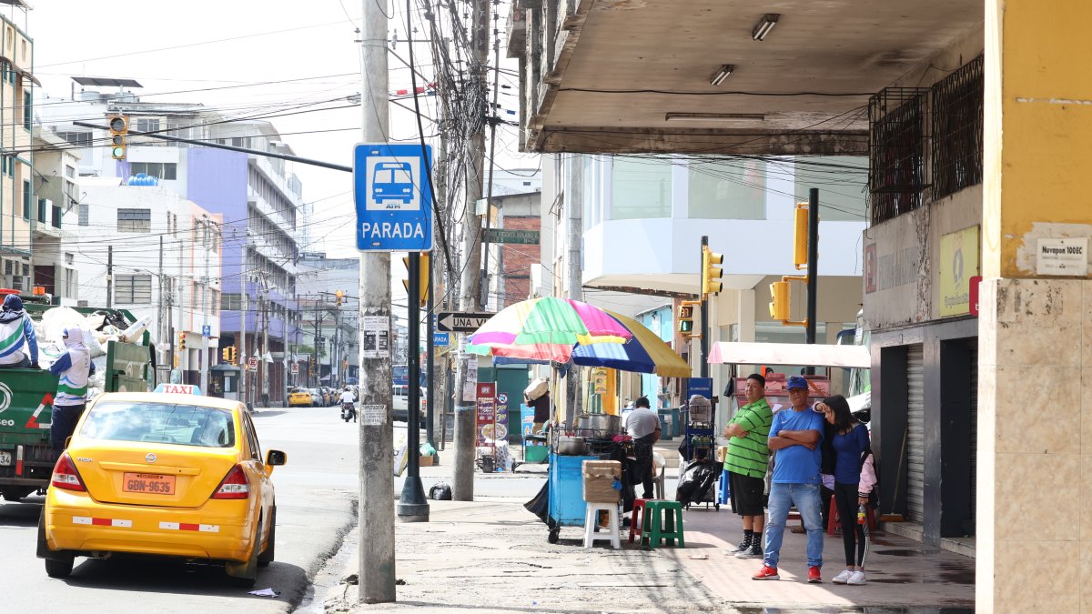 Espacios. Usuarios de buses se protegen de los rayos solares en los exteriores de un inmueble en el centro de Guayaquil mientras esperan por sus unidades.