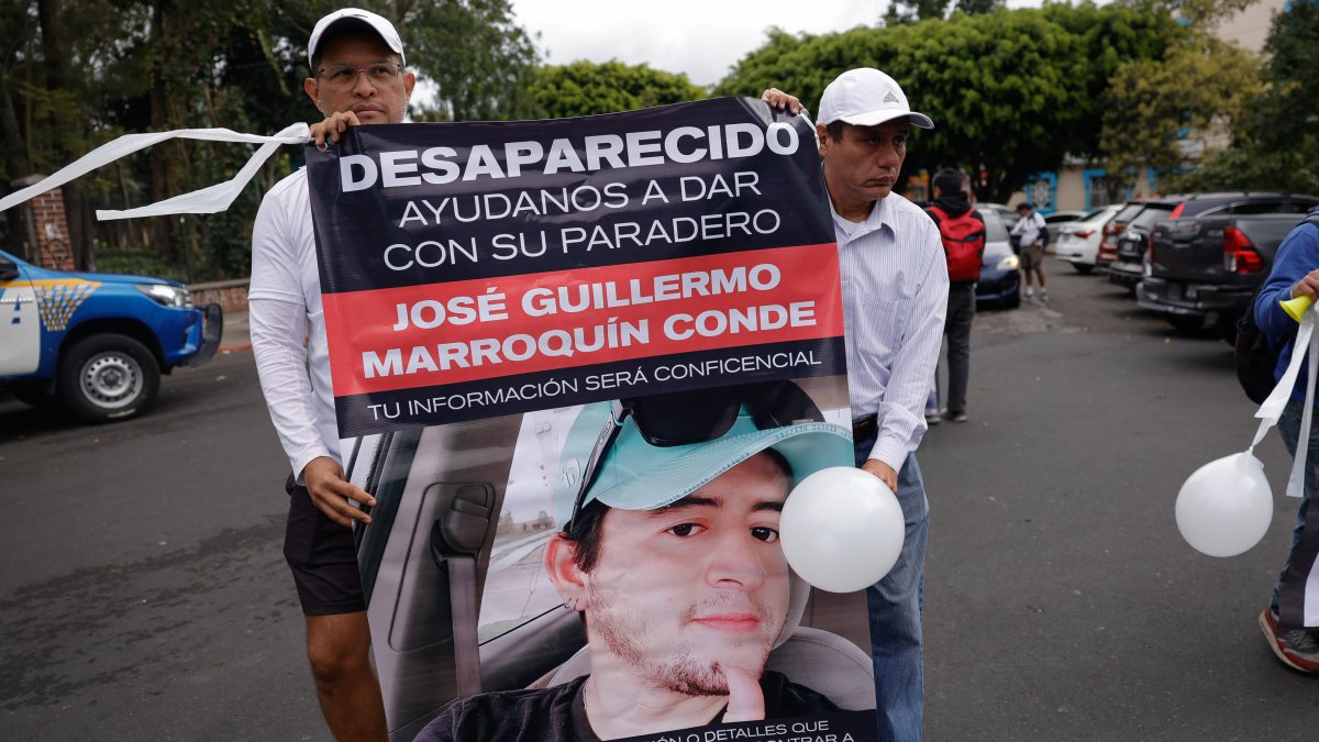 Familiares de Guillermo Marroquín muestran hoy un cartel con su retrato durante una marcha.