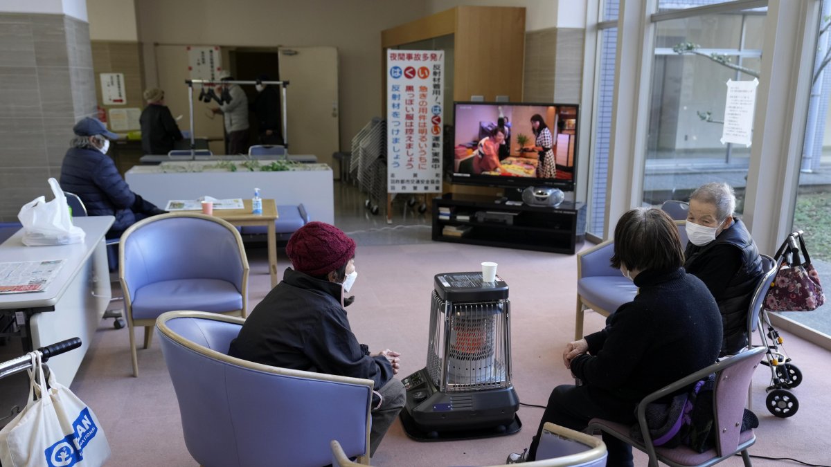 Shika. Un grupo de damnificados se sientan alrededor de un calentador en un centro de evacuación.