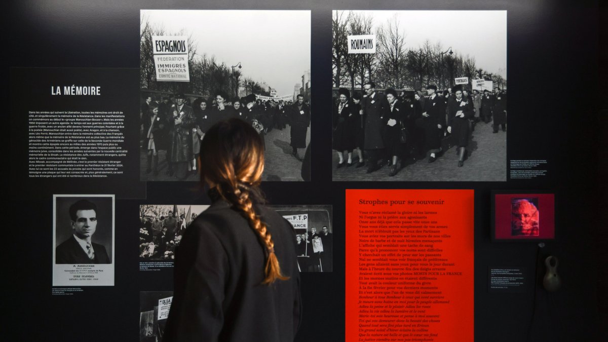 Una mujer junto a una fotografía impresa de Missak Manouchian (I), en la exposición 'Los extranjeros en la resistencia en Francia', en del Museo de la Shoáh, en París