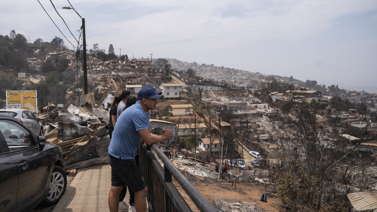 Personas observan viviendas destruidas en el sector de Achupallas, afectado por incendios forestales de Viña del Mar, Región de Valparaiso (Chile).