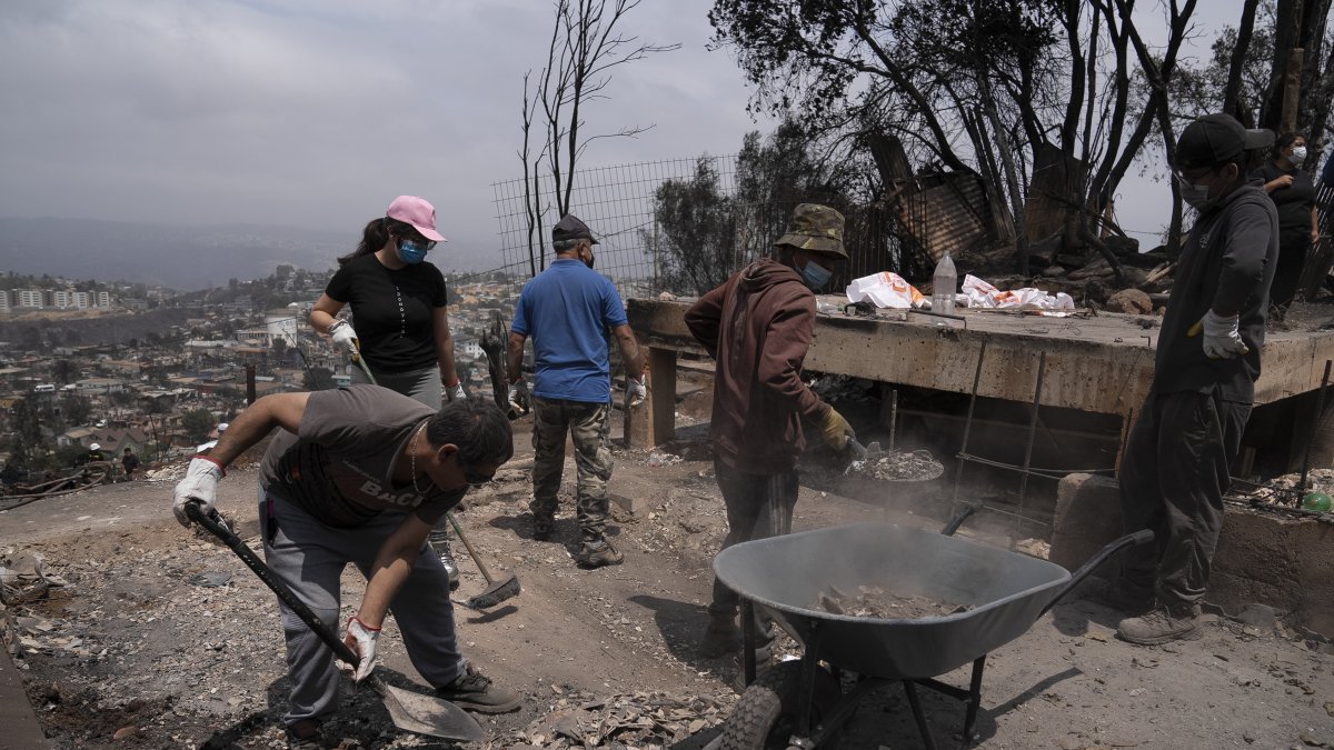 Un grupo de personas retiran escombros de una casa destruida en el sector de Achupallas, afectado por los incendios forestales, en Viña del Mar