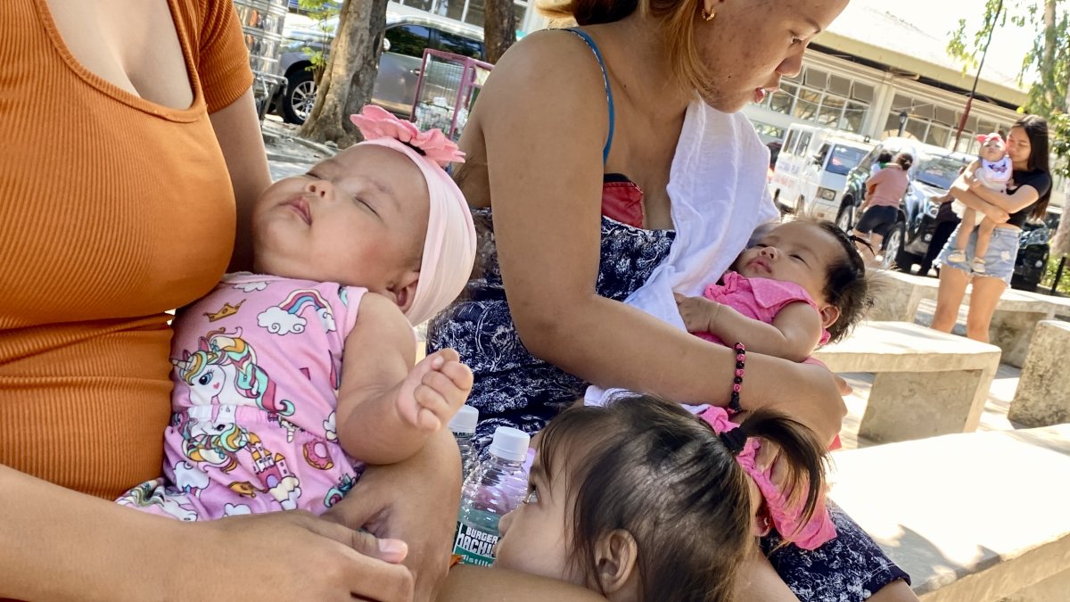 Madres filipinas y sus bebes en la entrada de un centro de salud.