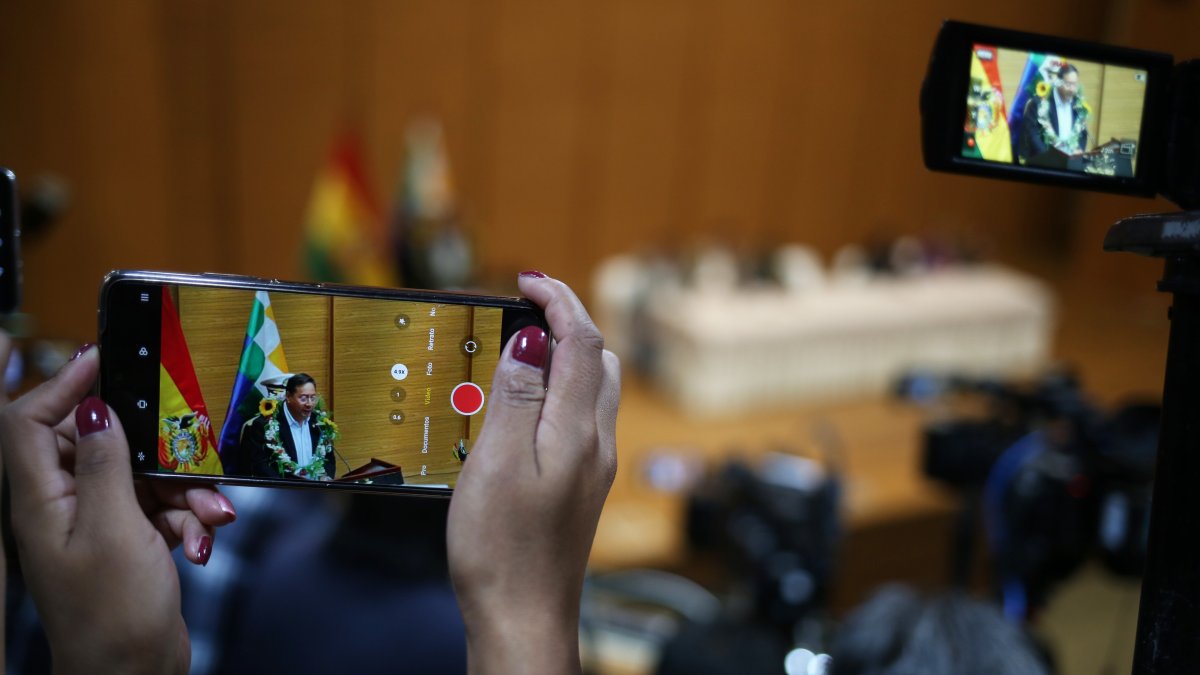 Una mujer graba con un teléfono al presidente de Bolivia Luis Arce durante la promulgación de la ley para elecciones judiciales este 6 de febrero de 2024, en la 'Casa Grande' en La Paz (Bolivia).