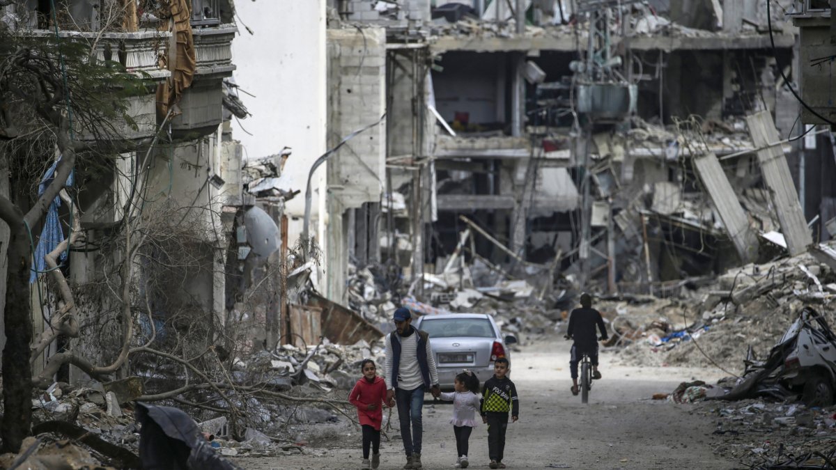 Al Bureije. Una familia palestina pasa junto a casas, en el sur de Gaza.