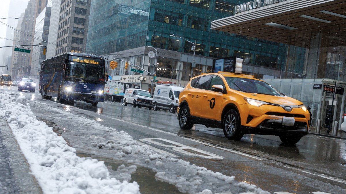 Nueva York. Varios vehículos circulan por la Sexta Avenida mientras cae nieve.