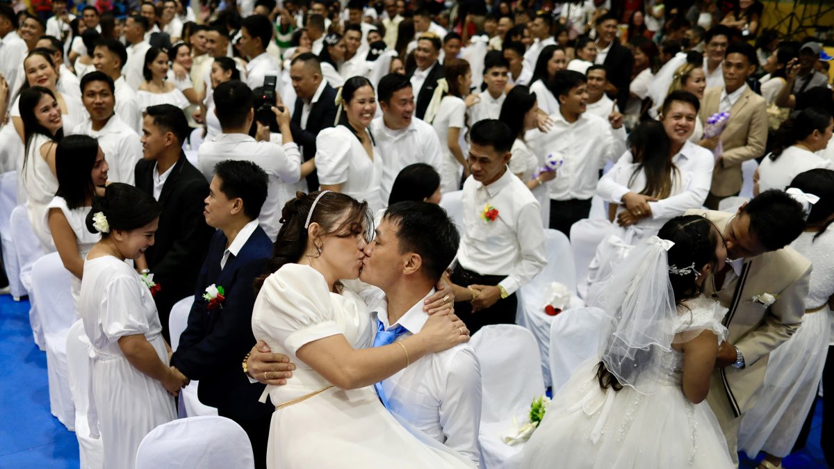 La pareja de novios Reynaldo Pingol y Maricel se besan durante una boda masiva el día de San Valentín en la ciudad de Bacoor.