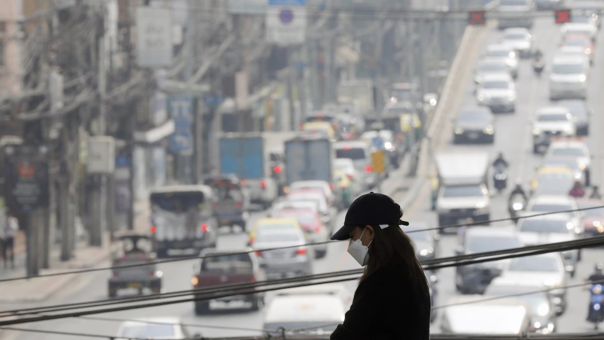 Una persona que lleva una máscara protectora camina mientras la fuerte contaminación del aire por partículas finas envuelve el cielo de Bangkok, Tailandia, el 15 de febrero de 2024.