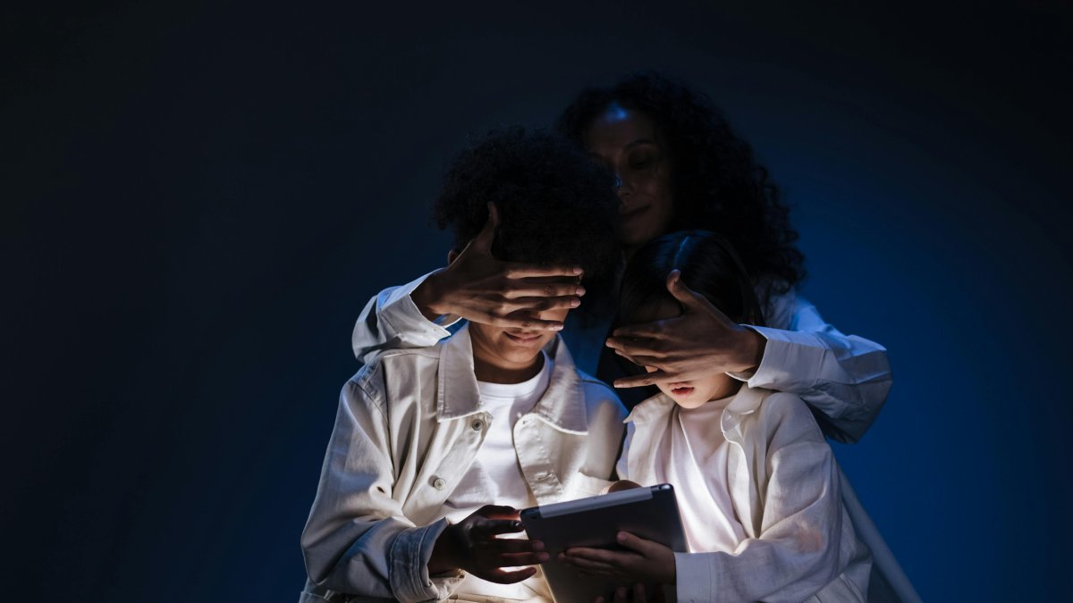 Una par de niños son contralados por una persona mayor, para evitar que sigan vinculados con un dispositivo electrónico.