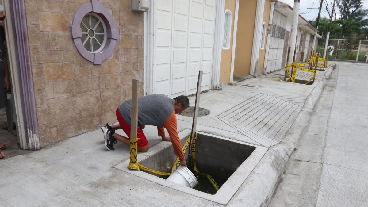 Los moradores de Samanes 6 utilizan baldes para sacar el agua que se estanca en lo que se supone deben ser jardineras.