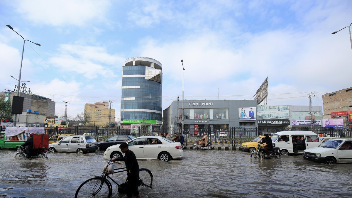 Trabajadores en una calle inundada durante un fuerte aguacero en Peshawar, Pakistán, el 19 de febrero de 2024.