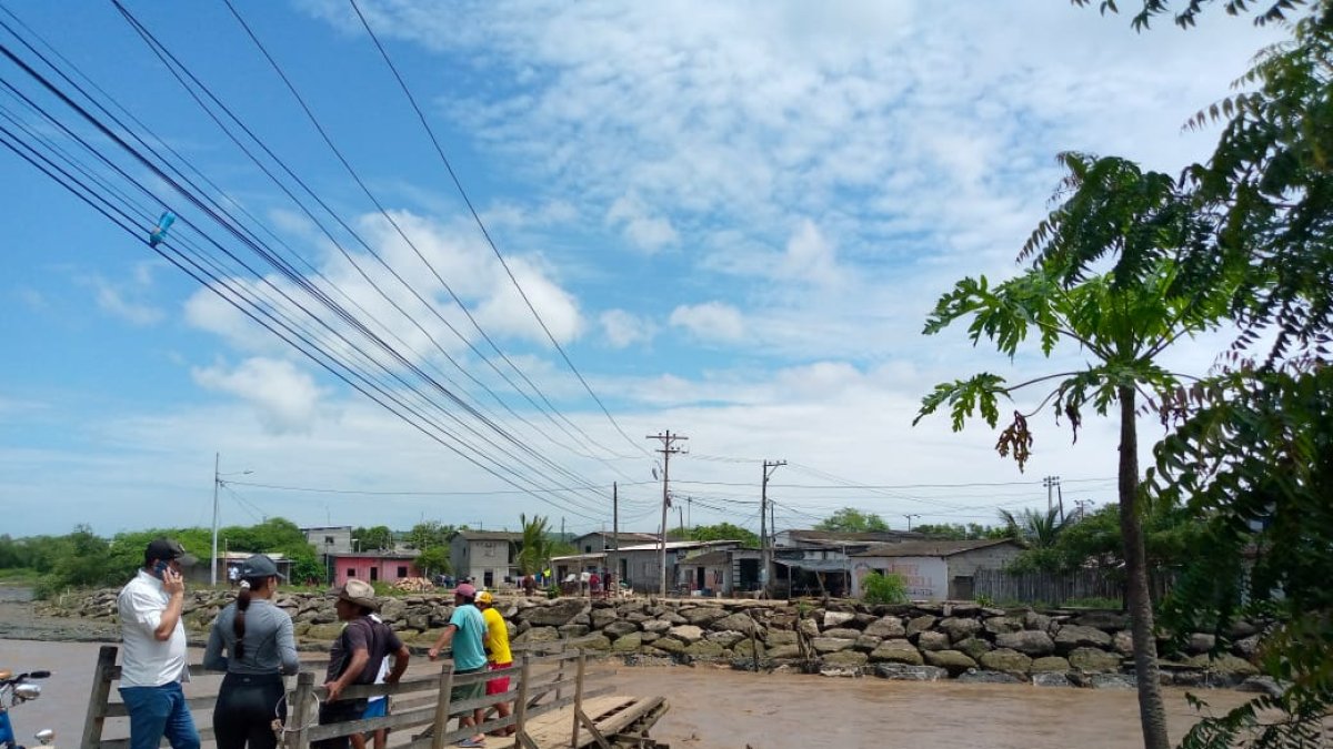 Un grupo de personas observa los restos de un puente de madera que cruzaba sobre el río Atravezado, en Libertador Bolívar, Santa Elena.