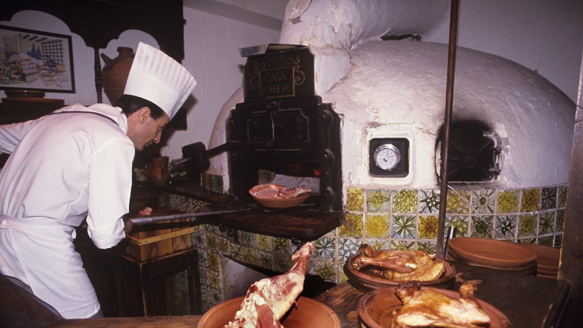 Un cocinero introduce una fuente en el horno de asar.