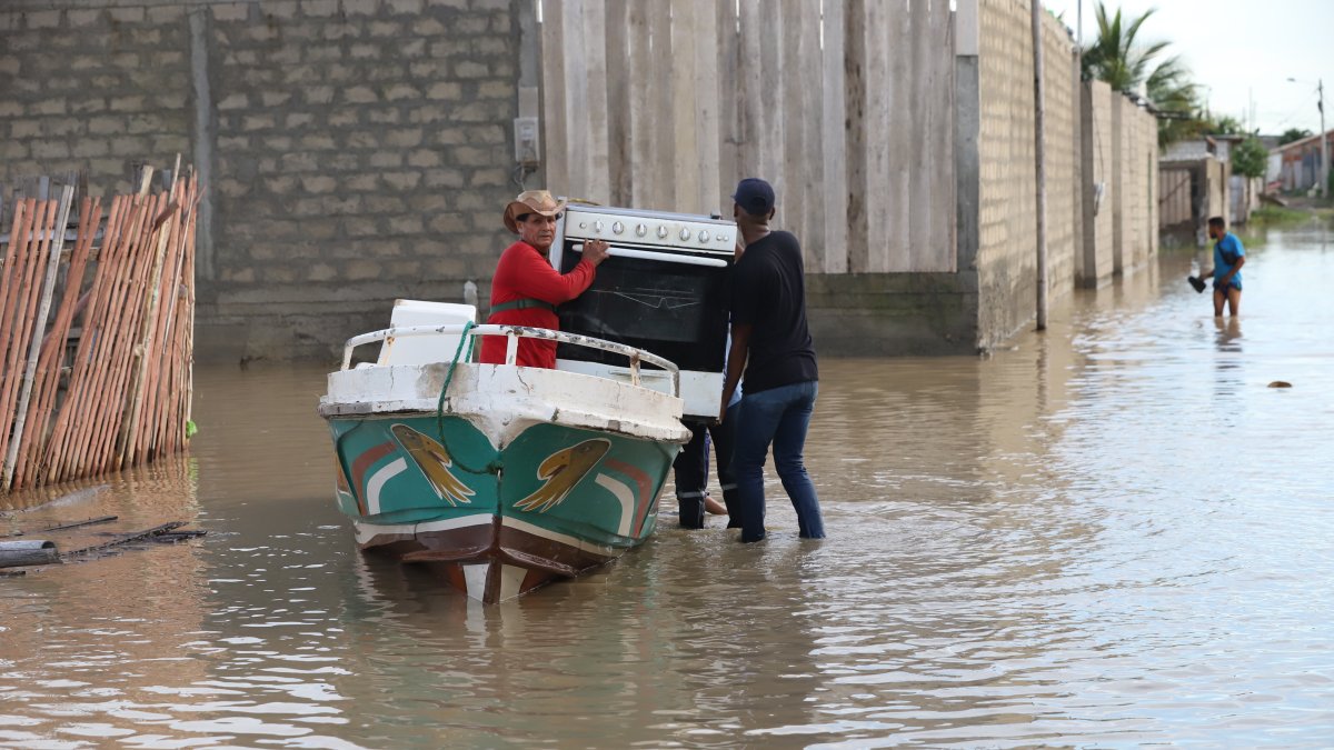 Un grupo de personas busca salvar una cocina en medio del agua que cubre una vasta zona de Playas.