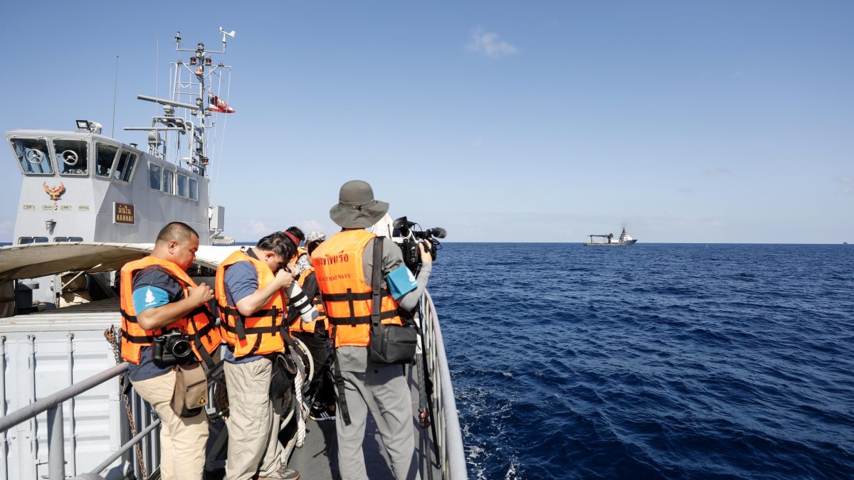 Medios de comunicación trabajan durante una operación conjunta de las Armadas tailandesa y estadounidense para rescatar los restos del barco.