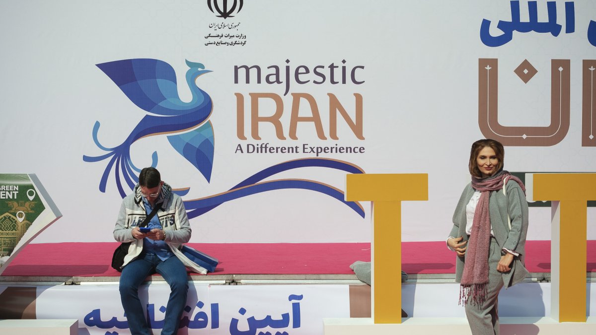 Una mujer. Posa frente al eslogan de la campaña turística oficial del país.