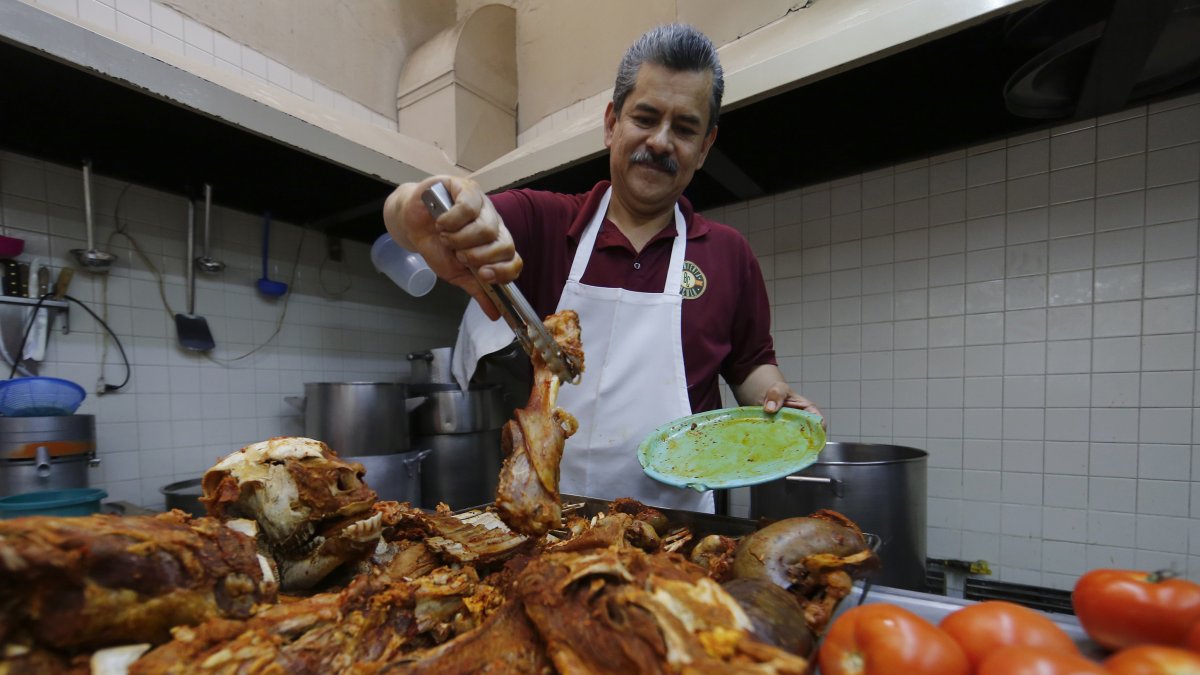 Un hombre cortando trozos de carne para elaborar birria en el comercio Birriería Cocula