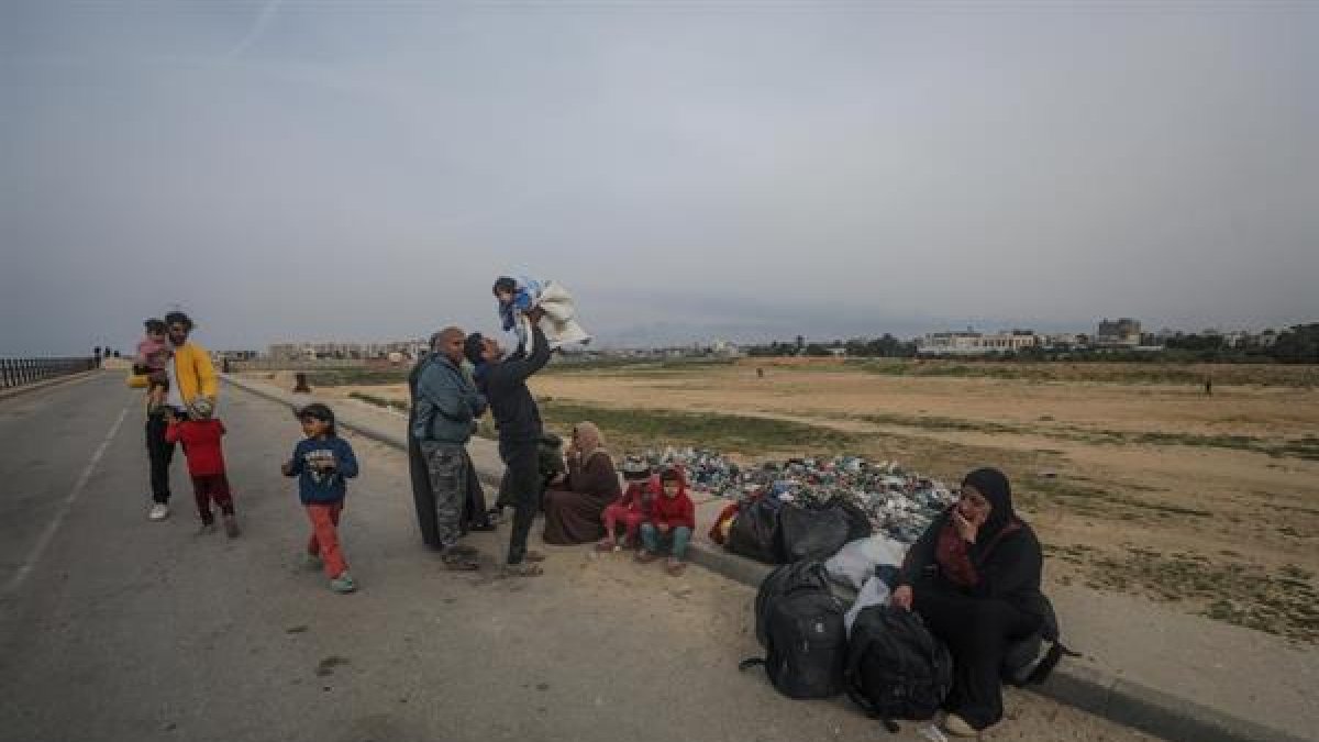 Un grupo de palestinos descansa tras cruzar desde el norte de la Franja de Gaza hacia el sur por la carretera Al Rashid, el 26 de febrero de 2024.