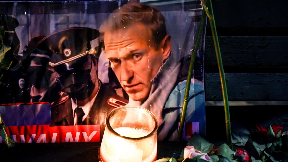 Un retrato del fallecido líder de la oposición rusa Alexei Navalny entre ofrendas florales y una vela frente a la embajada rusa en Berlín, Alemania.