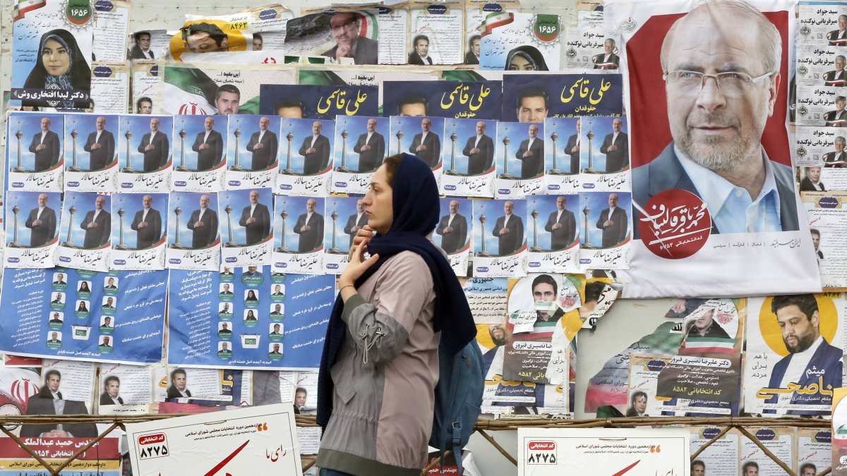Una mujer iraní pasa por delante de carteles electorales de candidatos a las elecciones parlamentarias que se celebran en Irán el 1 de marzo de 2024.