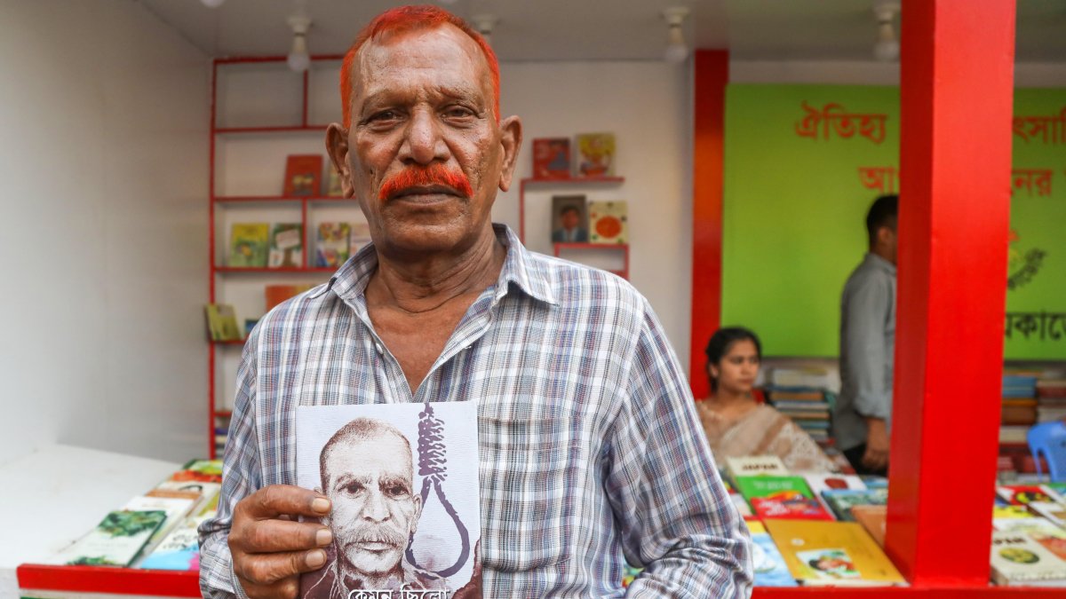Shahjahan Bhuiyan, con un ejemplar de su libro 'Cómo fue la vida del verdugo', en la caseta de la editorial Kingbondonti durante la feria anual del libro en Dacca, Bangladesh.