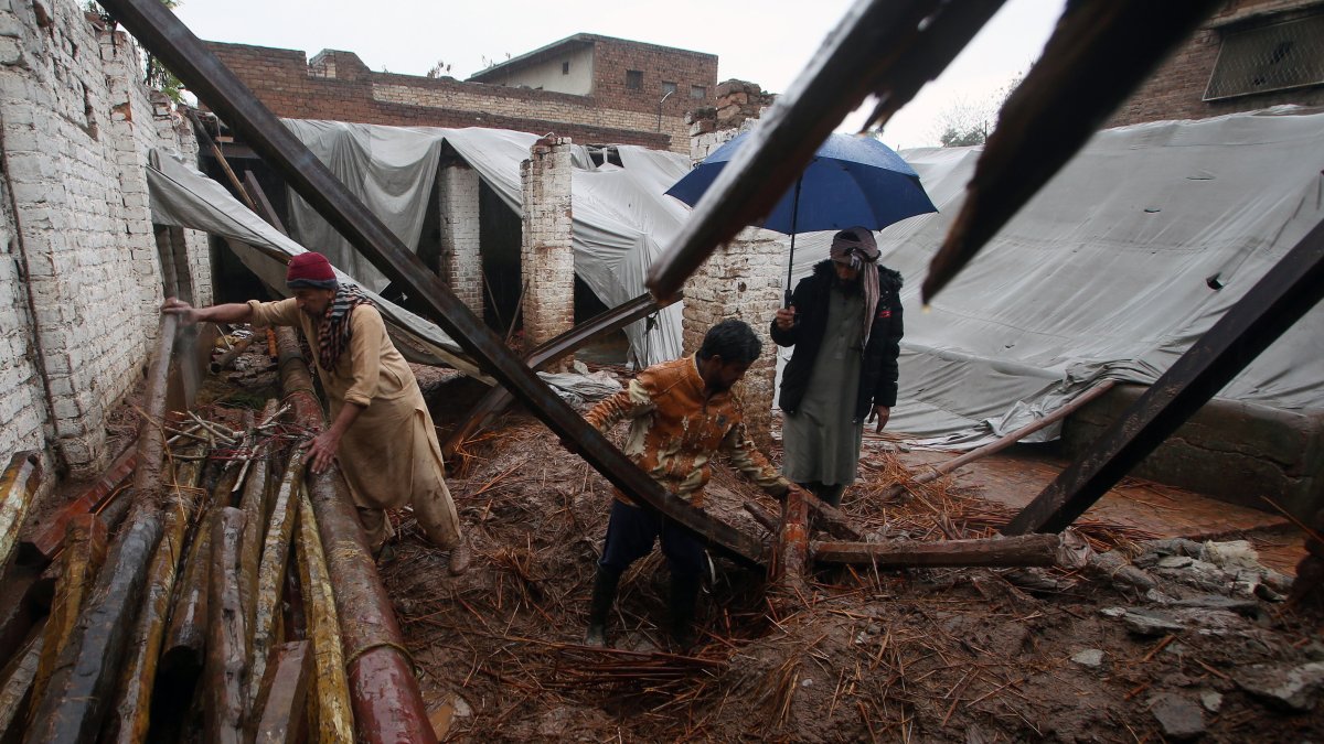 La gente recoge sus pertenencias de su casa que se derrumbó tras un fuerte aguacero en Peshawar, Pakistán,