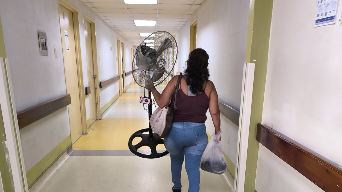 Una mujer lleva un ventilador a la sala donde está internado su paciente, en el hospital Teodoro Maldonado Carbo, del IESS.