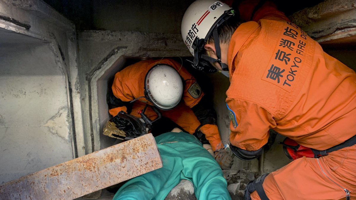 Efectivos del cuerpo de bomberos de Tokio llevan a cabo una demostración del rescate de una víctima atrapada bajo escombros.