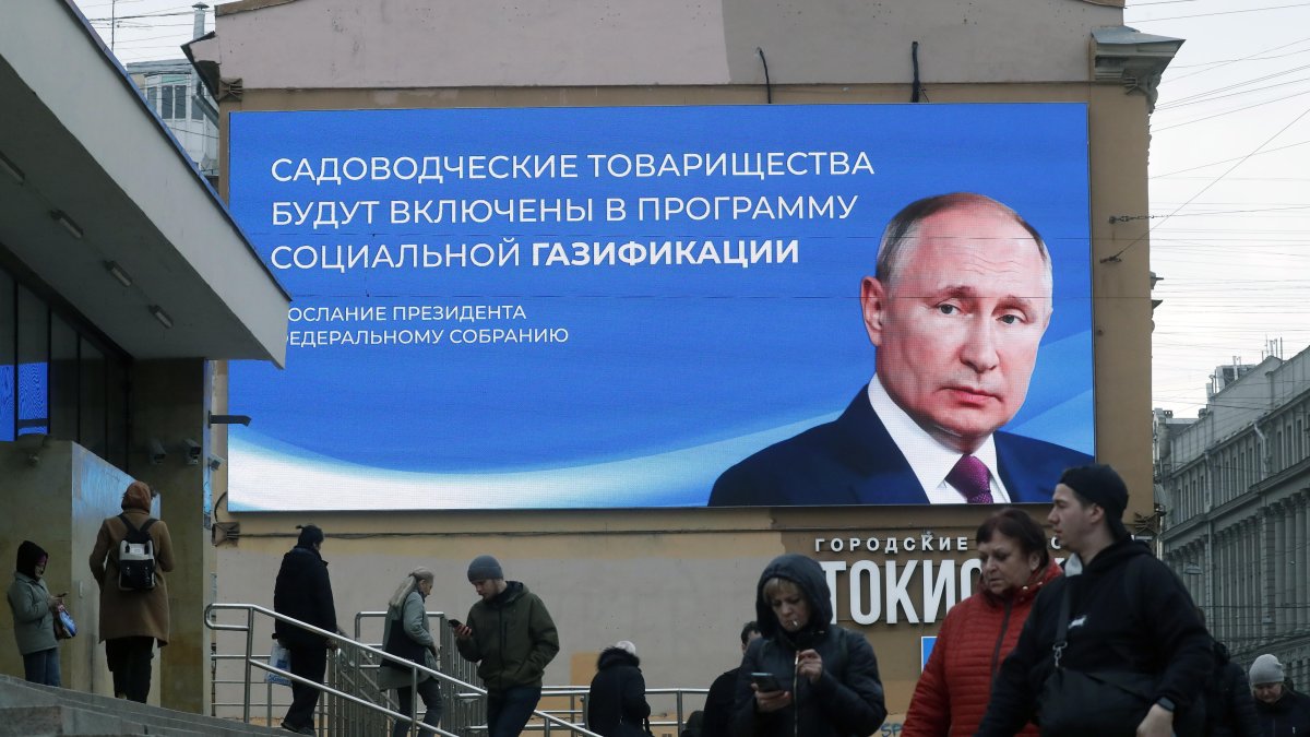 Ciudadanos pasan frente a una gigante pantalla digital con la imagen del presidente Vladimir Putin.