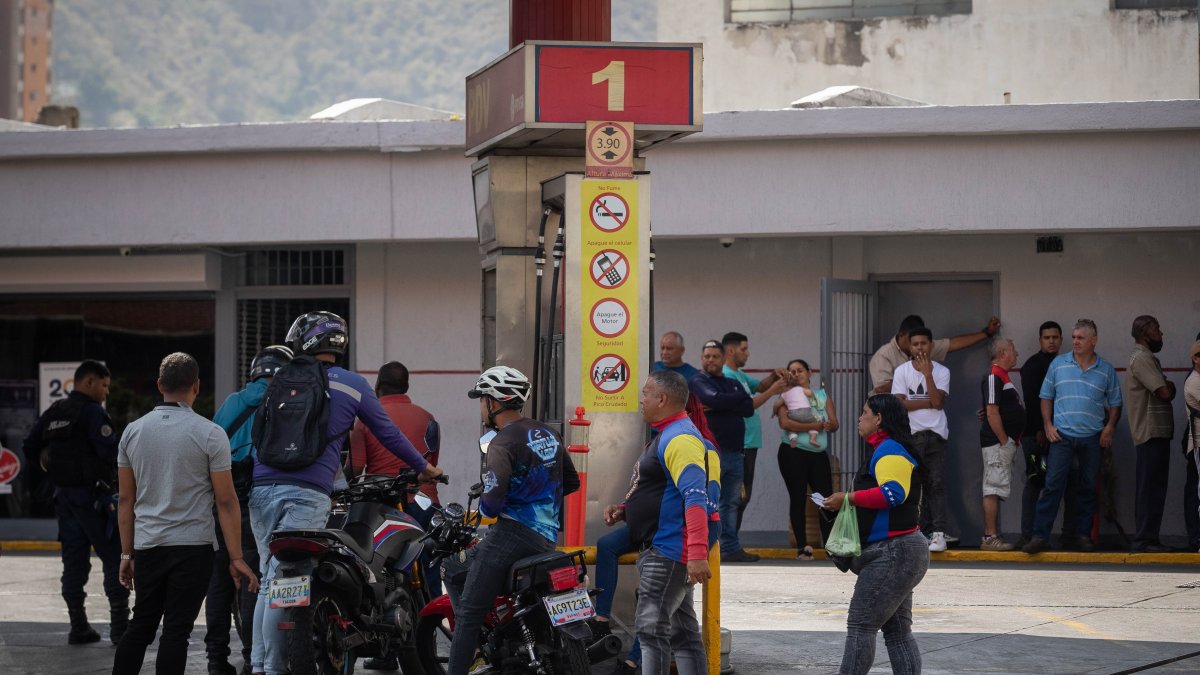 Varias personas hacen fila para abastecerse de combustible
