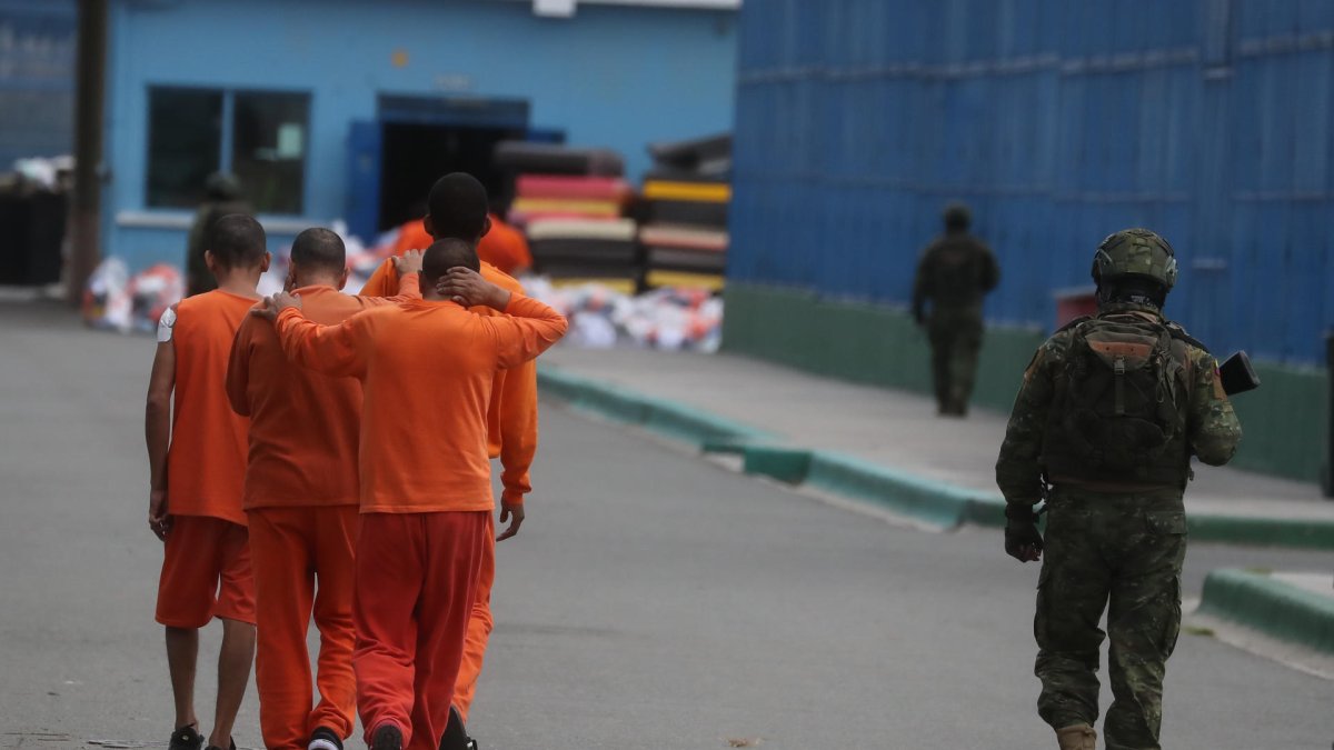 Un militar custodia a reclusos mientras se trasladan dentro de la cárcel de Cotopaxi.