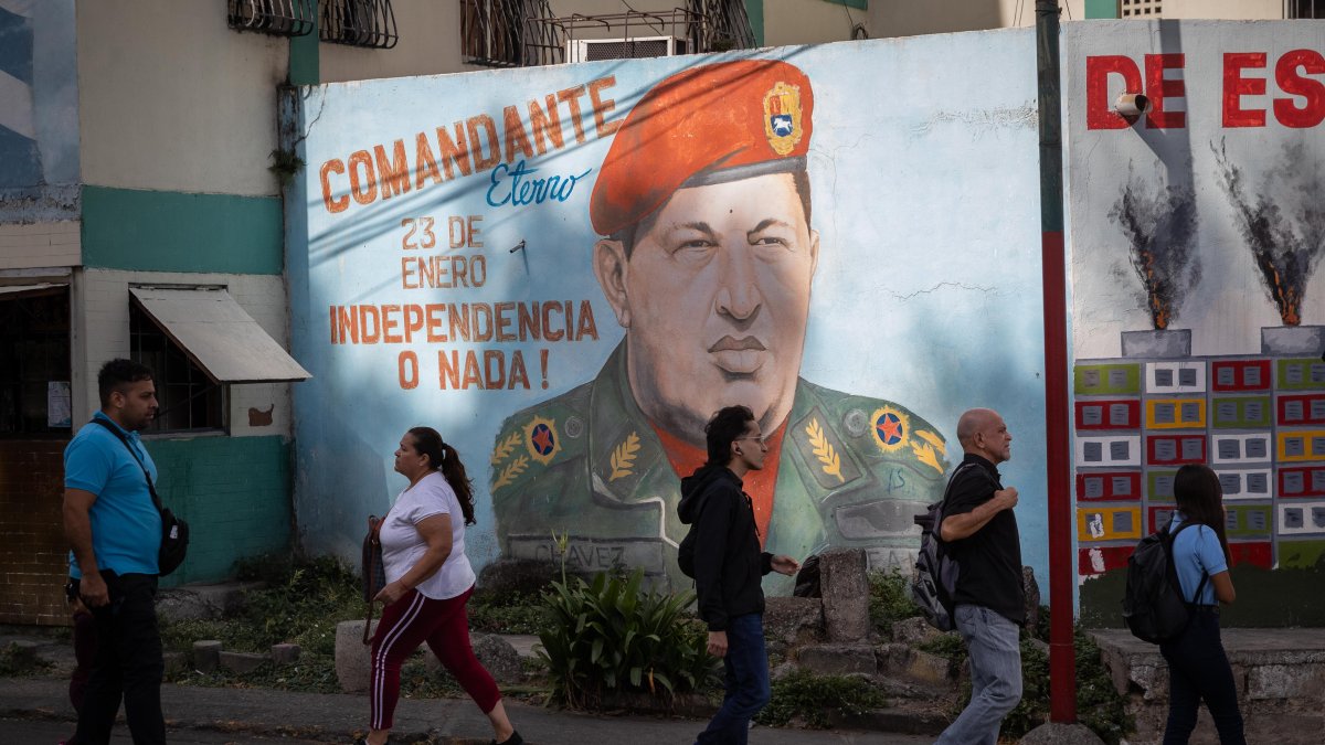 Caracas. Varias personas ladean un mural del fallecido Hugo Chávez.