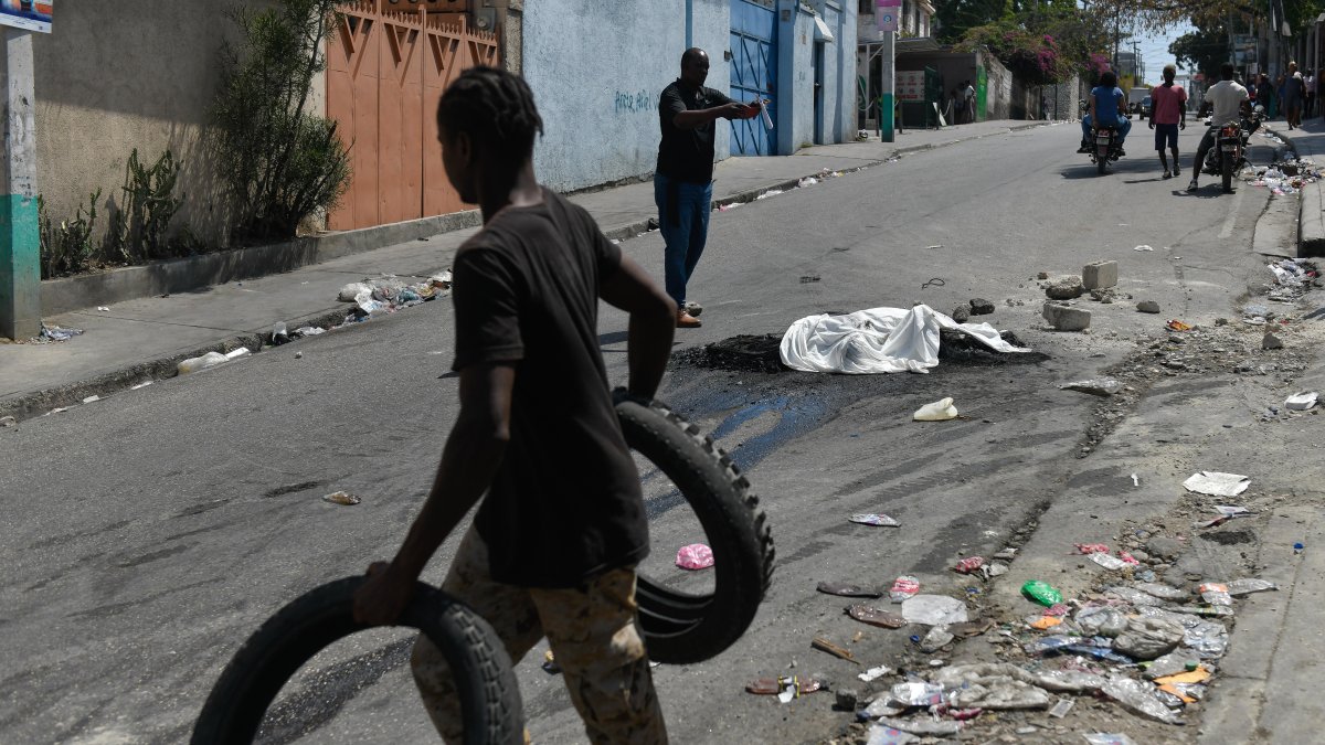 Transeúntes pasan junto al cadáver calcinado de una persona en la calle este miércoles 20 de marzo de 2024 en Puerto Príncipe (Haití).