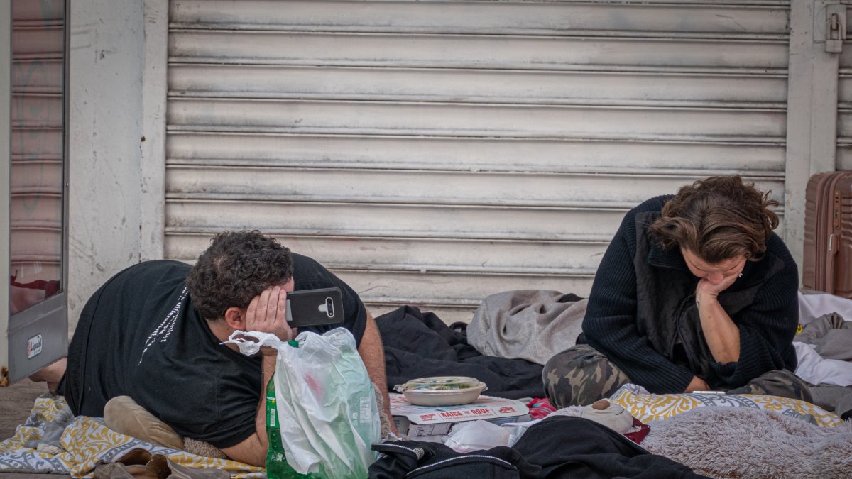 Varias personas sin hogar en la ciudad de Miami, ocupan un área pública.