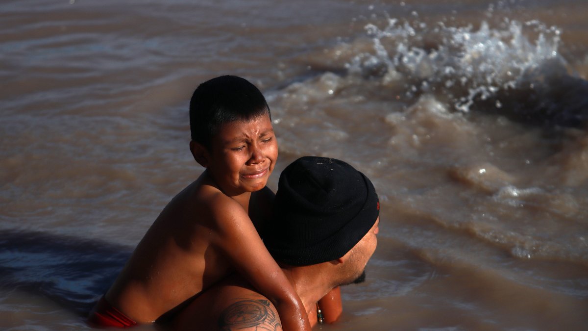 Un migrante con su hijo en la espalda cruza el Río Bravo, en la frontera que divide a México de los Estados Unidos