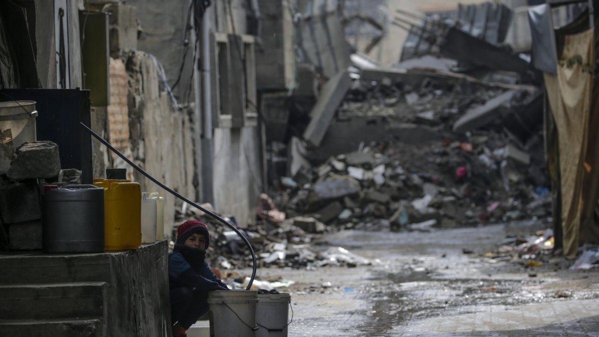 Un niño llena un cubo con agua entre los escombros de estructuras destruidas durante una operación militar israelí en el campo de refugiados de Al Nusairat, en el sur de la Franja de Gaza.