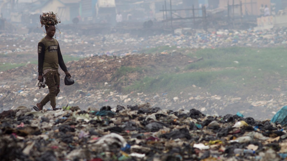 Un hombre transporta cables sobre su cabeza en el vertedero de Agbogbloshie, un barrio de Accra, capital de Ghana,