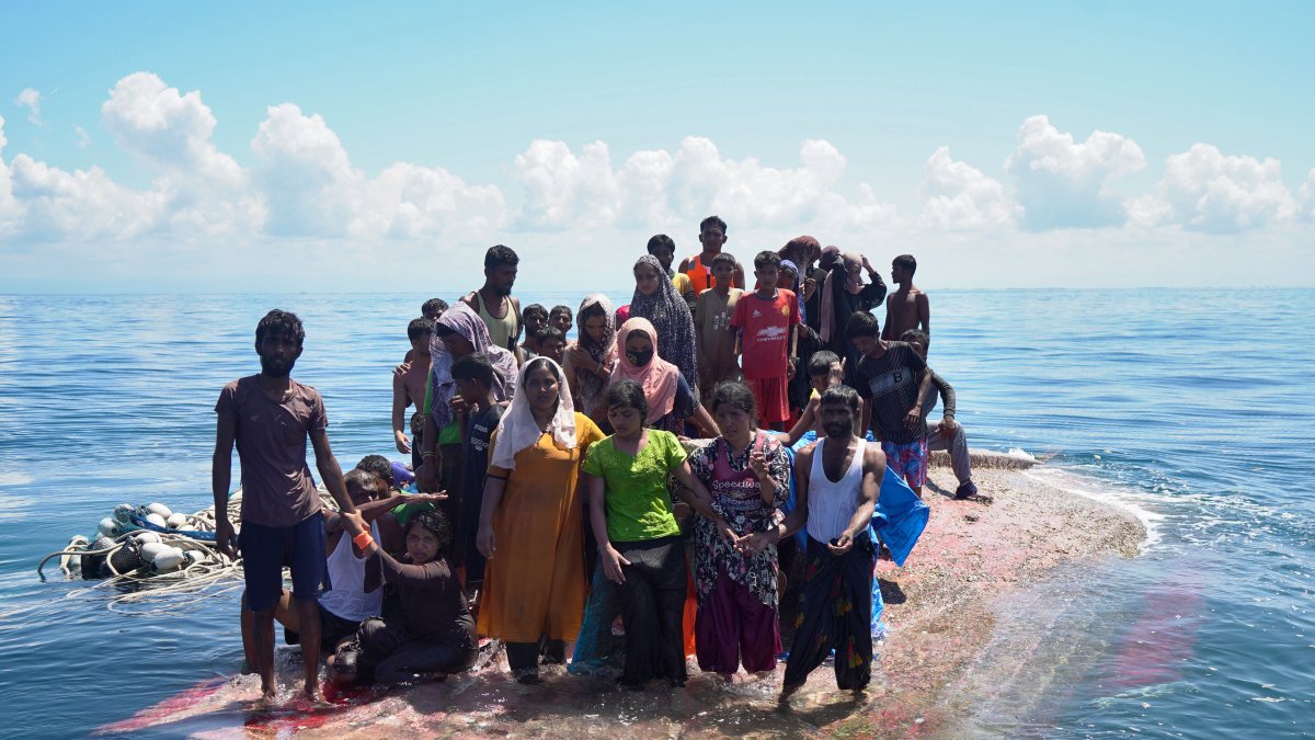 Supervivientes de un naufragio esperan sobre el casco de un barco volcado a ser rescatados en aguas cerca de Indonesia.