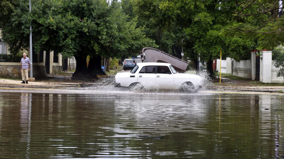 Un auto cruza por una calle anegada por las fuertes lluvias este sábado en La Habana (Cuba).