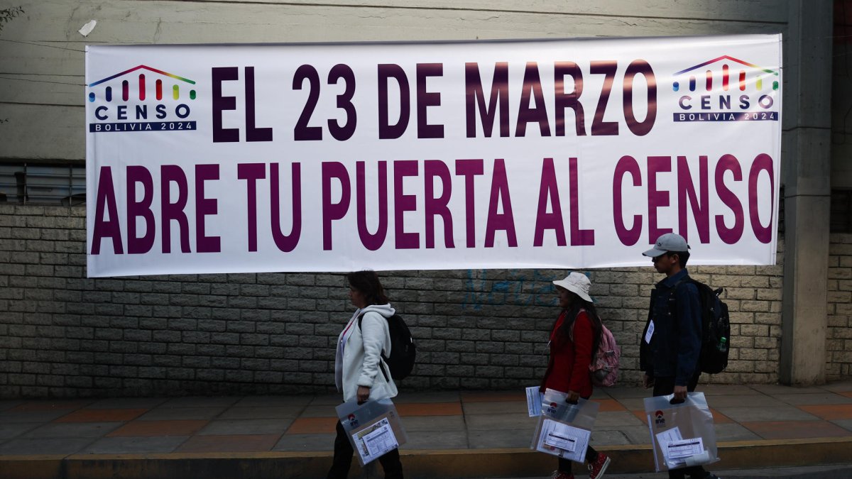 Voluntarios se desplazan por una calle durante el censo de población y vivienda este sábado 23 de marzo, en La Paz.