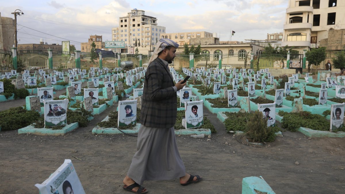 Una persona pasa junto a las tumbas de los combatientes hutíes en un cementerio dedicado a aquellos que murieron en la prolongada guerra del país, en Saná (Yemen).