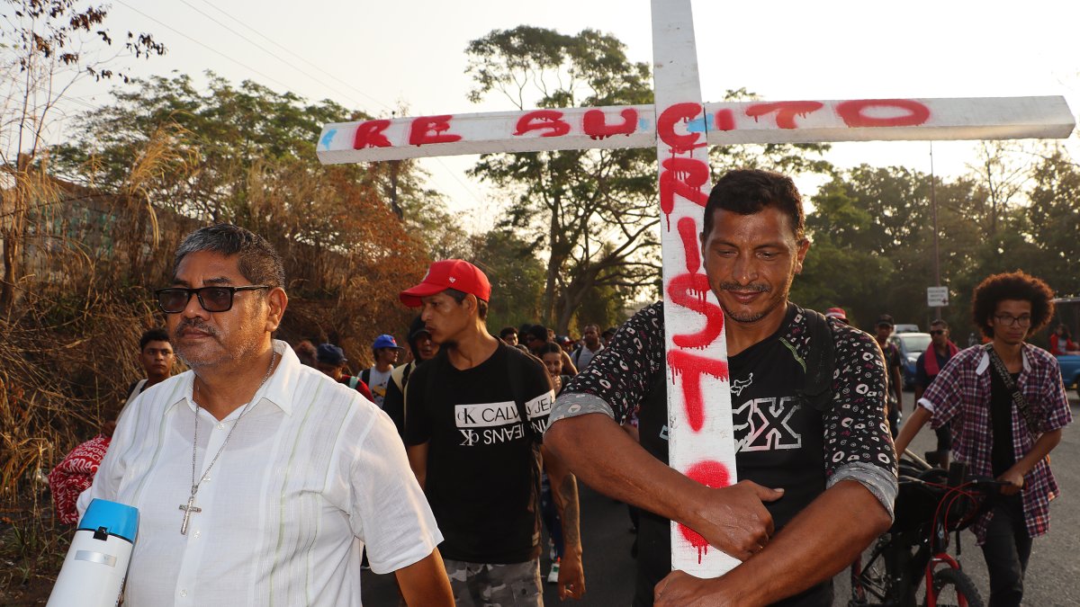 Un migrante sostiene una cruz durante una caravana que se dirige a Ciudad de México, este lunes en Tapachula (México).