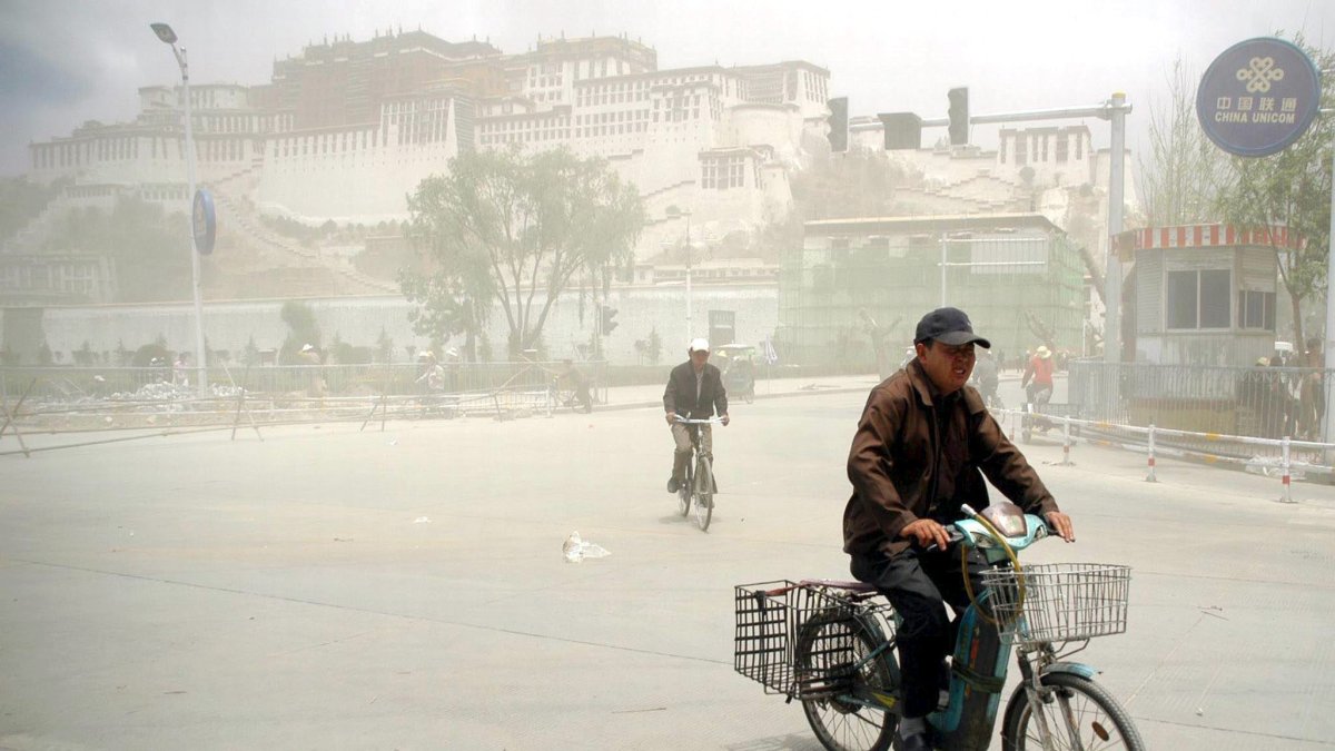 Un hombre sobre una bicicleta después de una tormenta de arena en China.