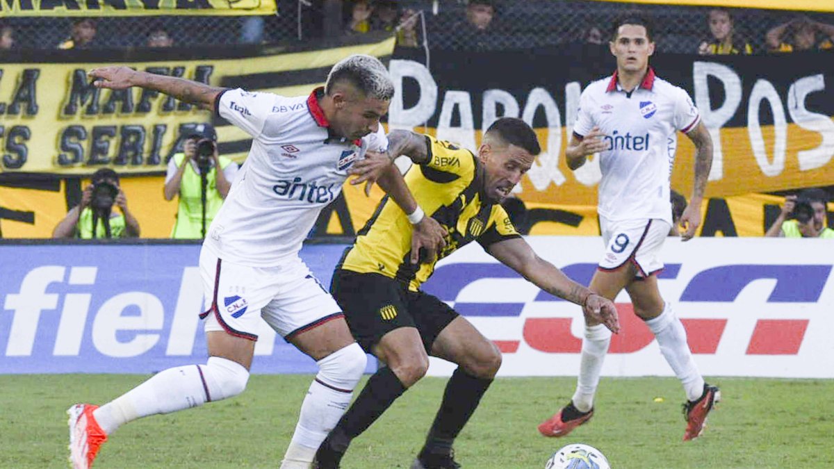 José Varela (d) de Peñarol disputa el balón con Mateo Antoni de Nacional.