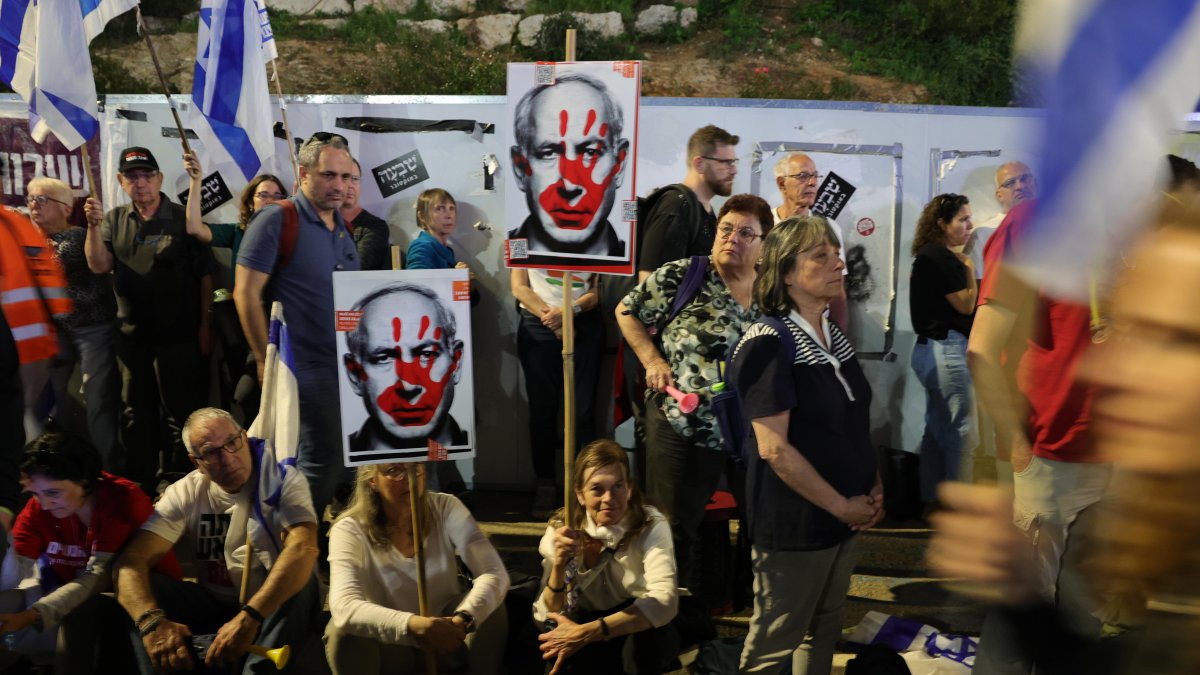 Manifestantes antigubernamentales sostienen banderas israelíes y pancartas con una imagen del Primer Ministro de Israel Netanyahu.
