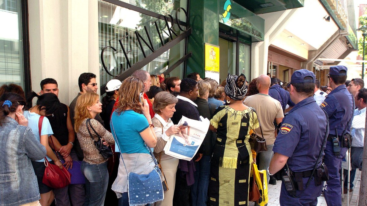 Cientos de inmigrantes haciendo fila para solicitar su regularización en España.
